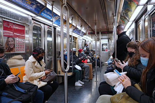 New York City, USA - November 16, 2021:  Passengers on the New York subway obey the rule requiring them to wear masks for pandemic safety.