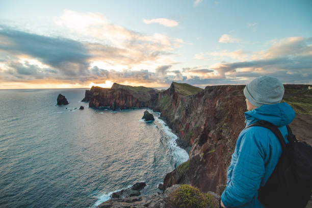 passionate traveller and hiker discovers the beauty of the ponta de sao lourenco area on the island of Madeira, Portugal at sunrise. View of a man admiring the beauty of the sunrise of the peninsula stock photo