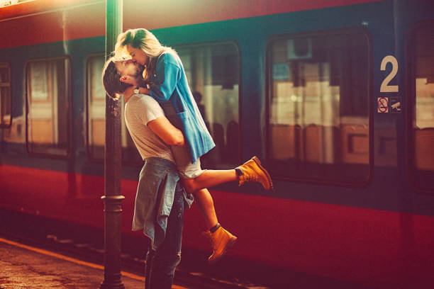 Passionate young man and woman kissing beside the train at the railway station stock photo
