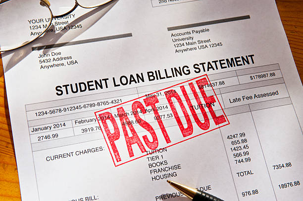 Past Due Student Loan Paperwork Statement for a Student Loan on a desktop.  Loan is PAST DUE with a red rubber stamp. Props include reading glasses, coffee cup and pen. Horizontal photograph. PAST DUE is bright red against the white form. Shot from a high angle looking down. Dramatic lighting with some shadows. student loan stock pictures, royalty-free photos & images