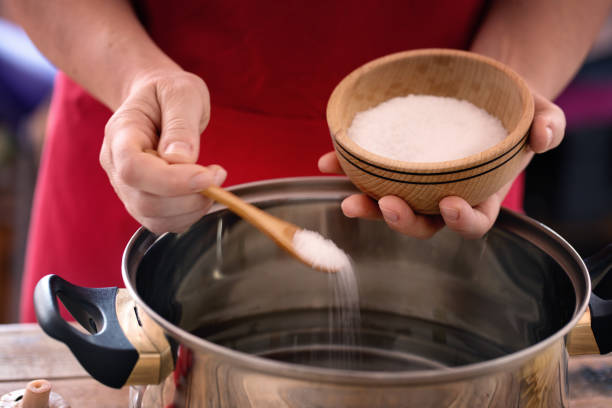 Pasta cooking - chef puts sea salt into boiling pot, close up stock photo