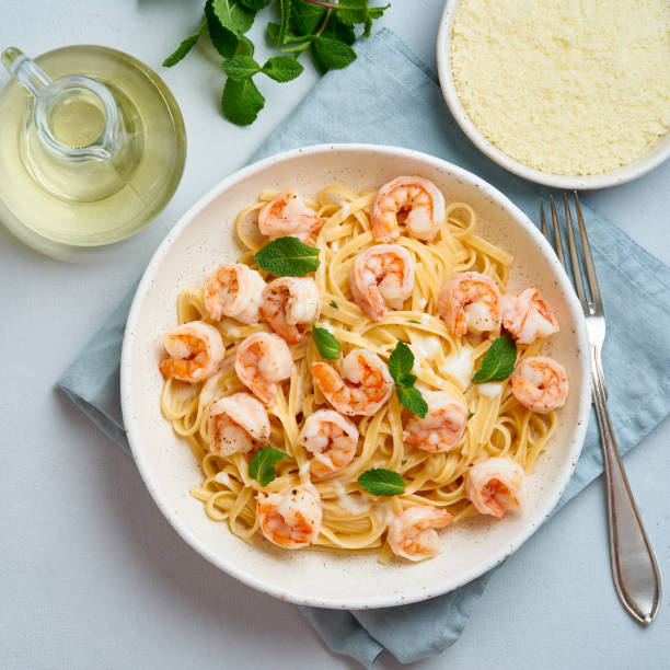 Pasta spaghetti with fried shrimps, bechamel sauce, mint leaf on blue table, top view, italian cuisine. stock photo