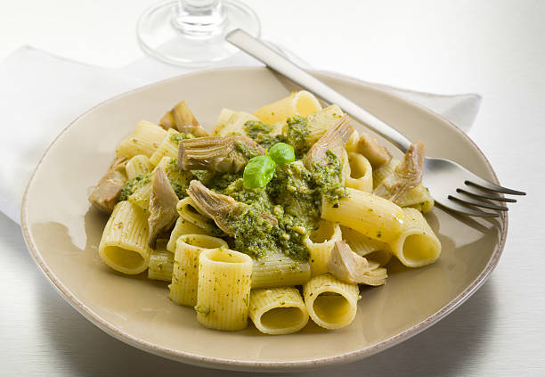 pasta with pesto and artichoke over steel background stock photo