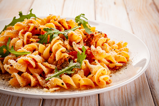 Pasta with pork, sauce and vegetables on color gradient background