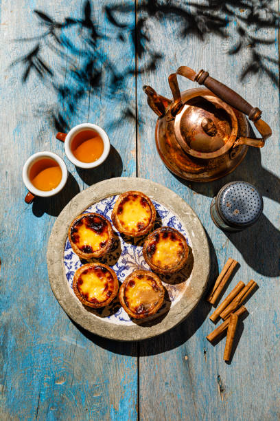 Pastel de Nata Fresh baked Portuguese egg custard Tart and Tea on blue wooden table stock photo