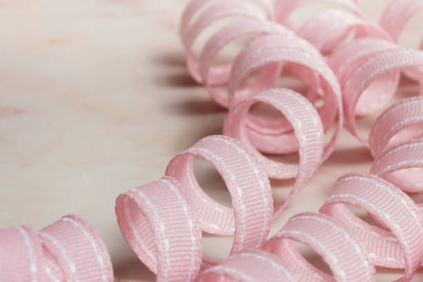 Pastel pink ribbon curl spirals on marble surface stock photo