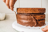 istock Pastry chef spreading chocolate cream on the edges of a chocolate cake indoors 1352160810