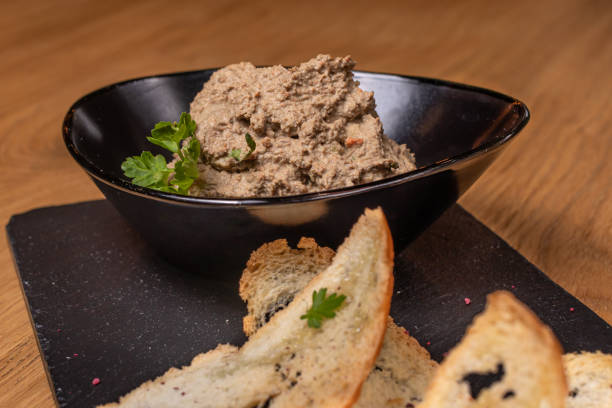 Pate of beef liver and meat with herbs in a black plate with crunchy toast. Restaurant food liver pâté photos stock pictures, royalty-free photos & images
