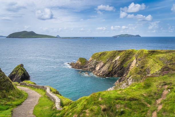 Path leading down to Dunquin Pier surrounded by turquoise water and tall cliffs, Dingle Path leading down to Dunquin Pier surrounded by turquoise water of Atlantic Ocean and tall cliffs, Dingle, Wild Atlantic Way, Kerry, Ireland dingle peninsula stock pictures, royalty-free photos & images
