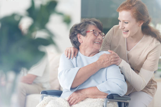 Patient and caregiver spend time together Happy patient is holding caregiver for a hand while spending time together home caregiver stock pictures, royalty-free photos & images