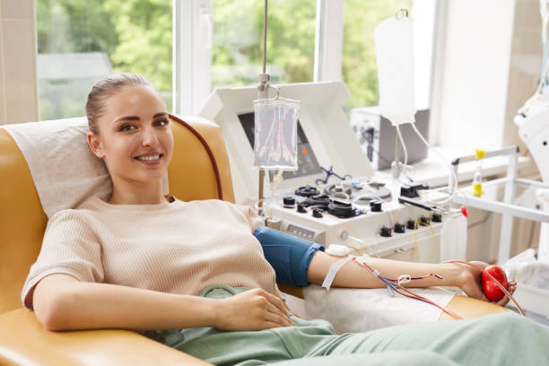 Patient donating blood at hospital Portrait of young woman smiling at camera while lying on the couch and donating the blood at hospital blood donation stock pictures, royalty-free photos & images