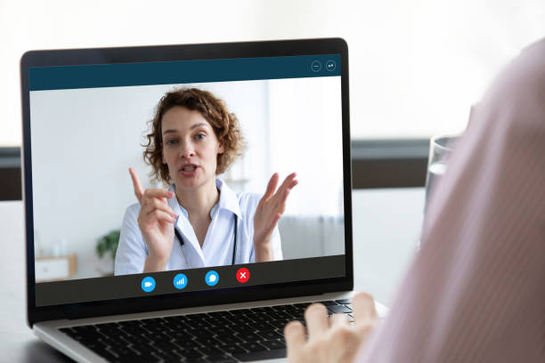 paciente tiene videoconsulta en línea con el médico en el ordenador portátil - nurse talking to camera fotografías e imágenes de stock