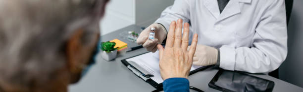 Patient refusing the coronavirus vaccine offered by doctor stock photo