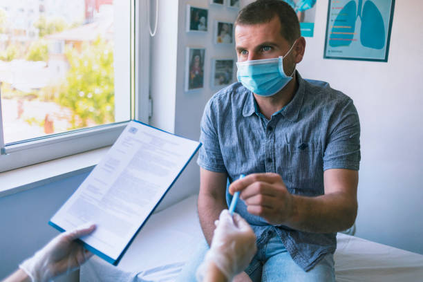 Patient wearing protective face mask filling out paperwork in a doctor's office stock photo