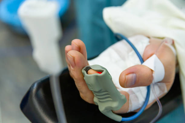patientâs hand with pulse oximeter on finger for monitoring in hospital - cor saturada imagens e fotografias de stock