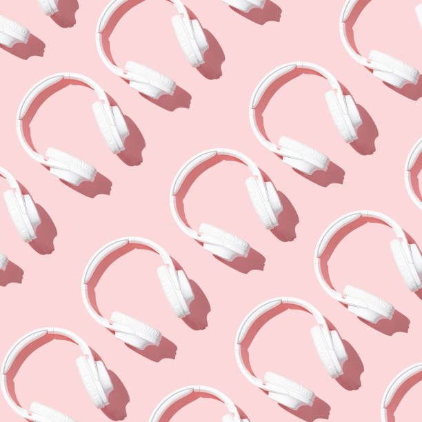 Pattern white headphones on modern pale pink table top view flat lay. Free space for creative design text and content stock photo