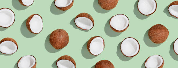 Pattern with ripe coconuts on green background. Top View stock photo