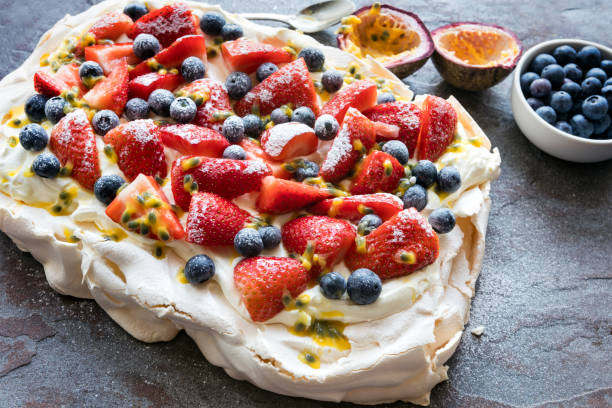 Pavlova Meringue Cake with Berries and Passionfruit Pavlova meringue cake with berries and passionfruit.  Side view on slate. pavlova dessert photos stock pictures, royalty-free photos & images
