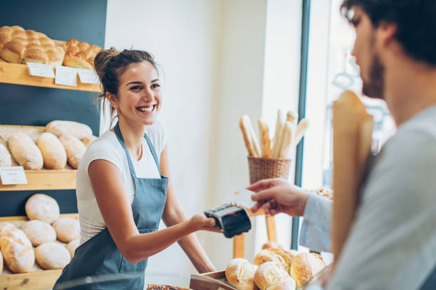 Paying with credit card for a baguette Customer making a credit card payment in a bakery credit card reader stock pictures, royalty-free photos & images