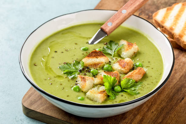 Pea soup. Green pea puree soup in a bowl served with grilled toasts, top view stock photo