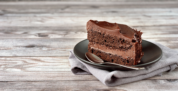 Sliced indulgent Chocolate cake against a rustic aged wooden surface.