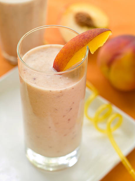 Peach smoothie Peach smoothie (or milkshake) in glass, selective focus peach smoothie stock pictures, royalty-free photos & images