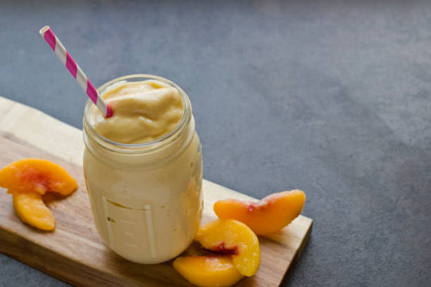 Peach Smoothie with Sliced Peaches A fruit smoothie with sliced peaches in a jar. peach smoothie stock pictures, royalty-free photos & images