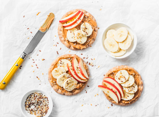 Peanut butter, apple, banana, flax and chia seed  crackers toast on a light background, top view Peanut butter, apple, banana, flax and chia seed  crackers toast on a light background, top view cracker snack photos stock pictures, royalty-free photos & images