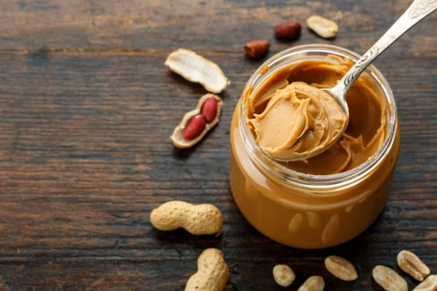 peanut paste in an open jar and peanuts stock photo