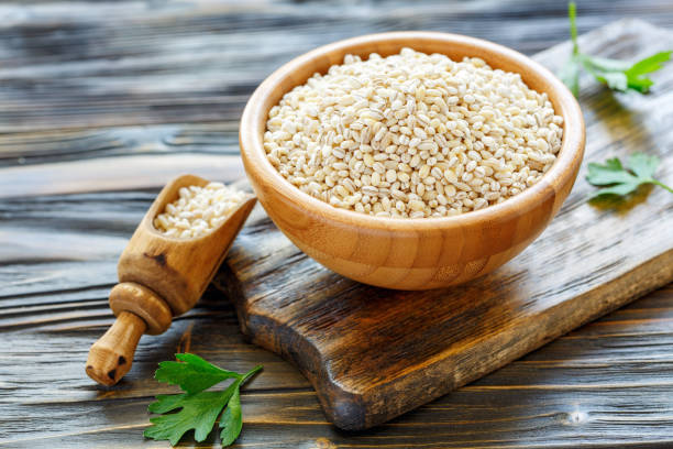 Pearl barley in a wooden bowl and scoop with barley. stock photo