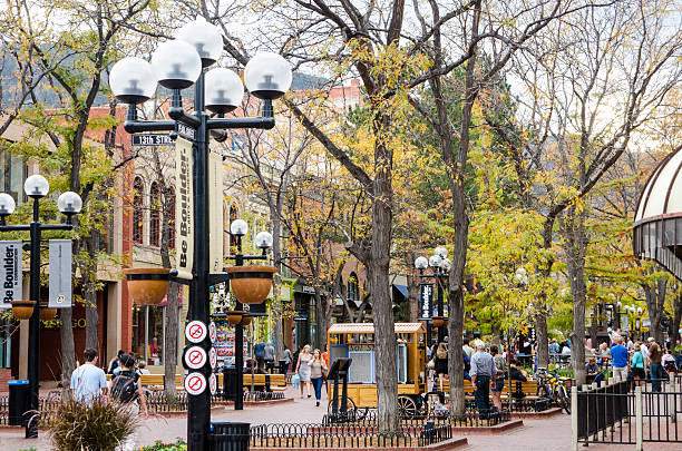 Pearl Street Mall in Downtown Boulder, Colorado Boulder, Colorado, USA - October 18, 2015: People gather on Pearl Street on a beautiful Fall evening. The Pearl Street Mall, also referred to as Pearl Street, or Downtown Boulder, is a four block pedestrian mall in Boulder, Colorado. The pedestrian area stretches from 11th Street to 15th Street along Pearl Street and is home to a number of businesses and restaurants as well as the Boulder County Courthouse. The Pearl Street Mall is a popular destination for tourists visiting Boulder and for students attending the nearby University of Colorado Boulder. The mall hosts a blend of locally-owned businesses and national chain stores and restaurants. It is also home to much of Boulder’s nightlife. During the summer months, Pearl Street Mall is the stage for a number of street performers, including musicians. It is also a favorite gathering spot for many of Boulder’s homeless people. boulder colorado stock pictures, royalty-free photos & images