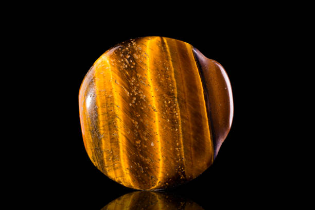 Pebble of tiger eye mineral Pebble of tiger eye mineral on black semi precious gem stock pictures, royalty-free photos & images