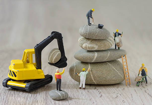 Pebbles stack and figurines workers Pebbles stack and figurines of construction workers figurine stock pictures, royalty-free photos & images
