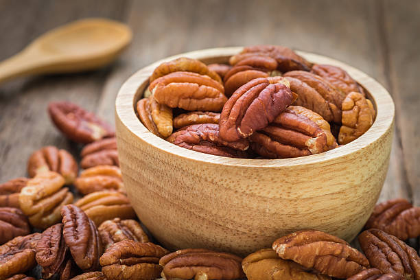 pecan nuts in wooden bowl - pecannoot stockfoto's en -beelden