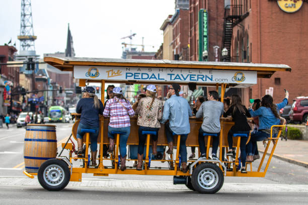 A Pedal Tavern party bike on a beautiful sunny day crossing Broadway. Nashville, Tennessee - March 25, 2019 : A Pedal Tavern party bike on a beautiful sunny day crossing Broadway. broadway nashville stock pictures, royalty-free photos & images