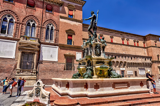 Bologna, Italy - July 9, 2022: Pedestrians along the busy streets in Bologna at the Statue of Neptune