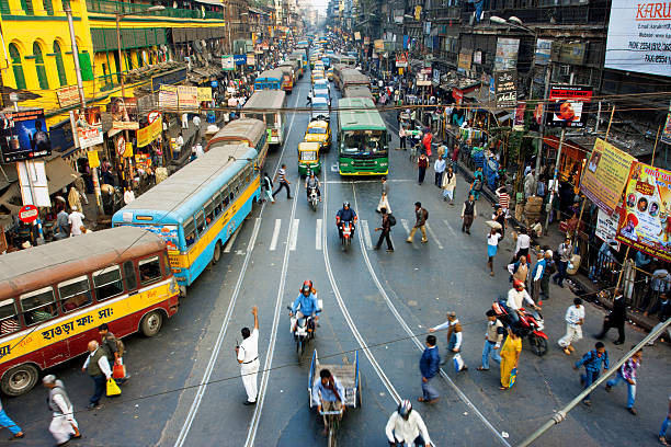 Pedestrians cross road in front of motorcycles, cars in India stock photo
