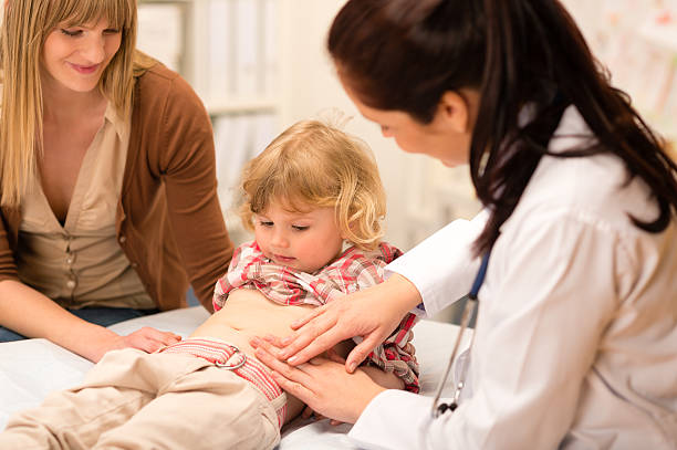 Pediatrician examine child tummy at office stock photo