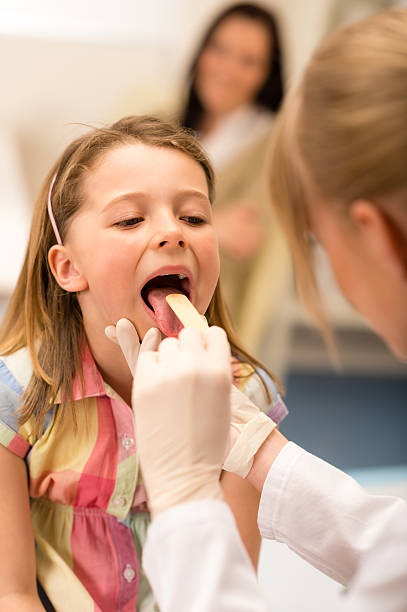 Pediatrician examine girl throat tongue stock photo