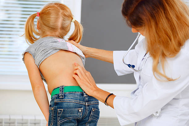Pediatrician examining little girl with back problems. stock photo