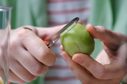 Human hands are peeling a kiwi fruit for detox smoothie