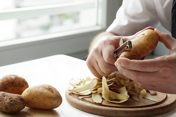 Peeling and preparing potatoes at home series stock photo
