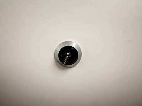 A peephole in a white door.