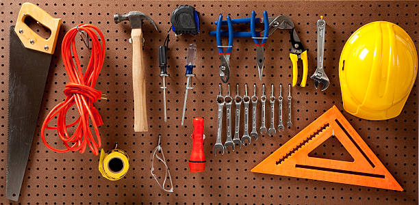 Peg board with tools and hard hat Peg board with hardhat, extension cord, flashlight, hammer, screw driver, caution tape, carpenter's square and pliers pegboard stock pictures, royalty-free photos & images