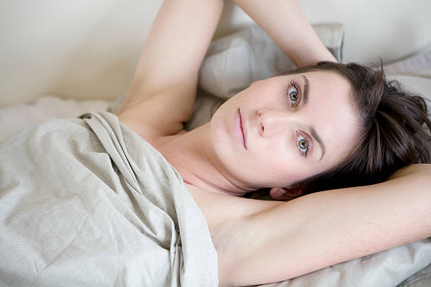pensive brunette woman lying on bed stock photo