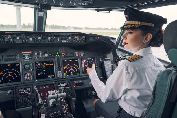 Pensive dark-haired woman co-pilot seated in the cockpit stock photo