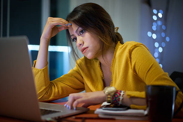 Pensive Girl College Student Studying At Night Young woman with laptop computer for homework. Tired hispanic girl and college education. Female student studying and using pc at home getting headache banging your head against a wall stock pictures, royalty-free photos & images