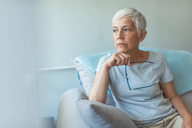 Pensive woman. Feeling Down. Middle aged woman in glasses looking down. Portrait of pensive worried senior woman looking through the window and thinking. Pensive woman. older women stock pictures, royalty-free photos & images