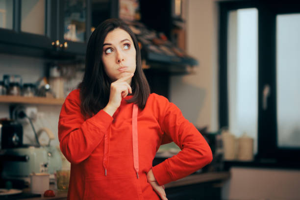 Pensive Woman Standing in the Kitchen Thinking about Food stock photo