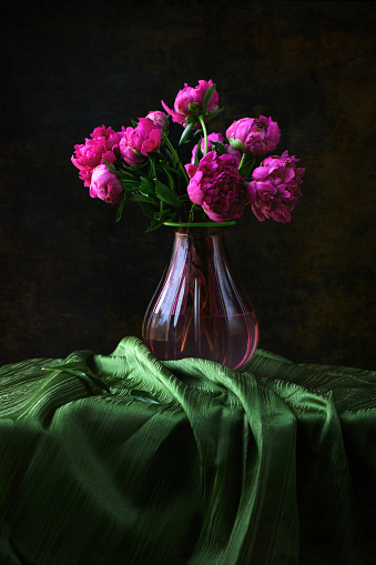 A pink glass vase with beautiful pink peonies.
